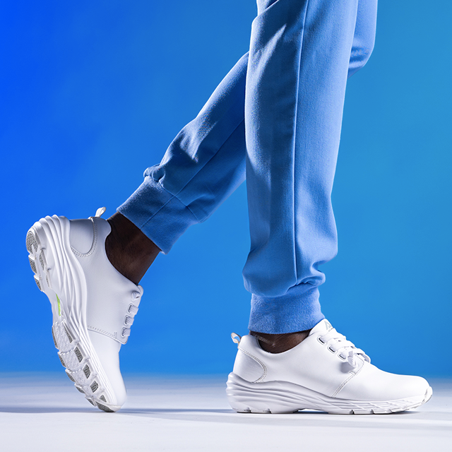 Align Velocity sneaker in white on foot, on a blue background. Back foot is in the air slightly, with toe touching the ground. Front foot is flat on the ground.