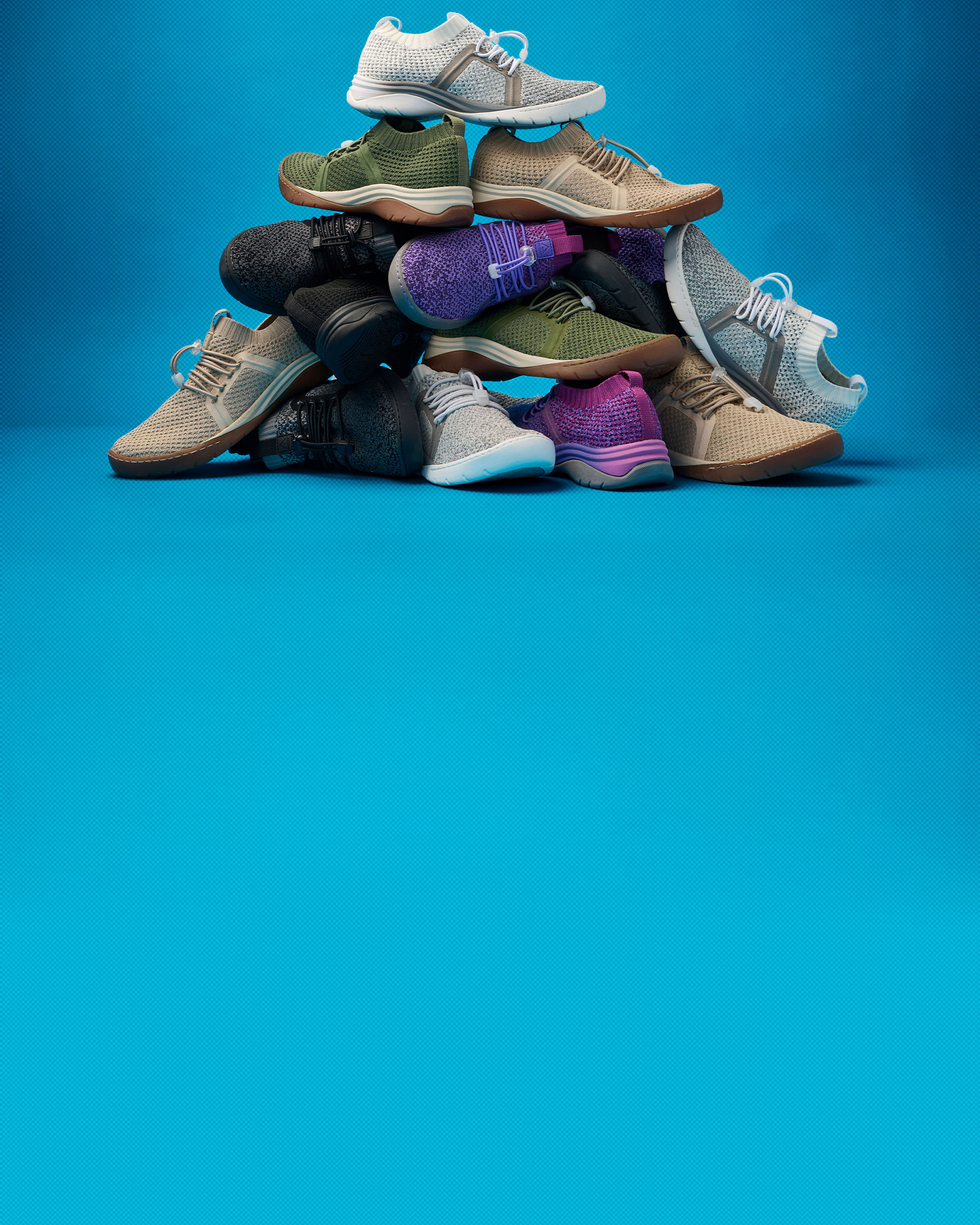 Various colors of the Align&trade; Torri knit sneaker stacked on top of each other in a messy pyramid, with Grey Cloud Ombre on top.