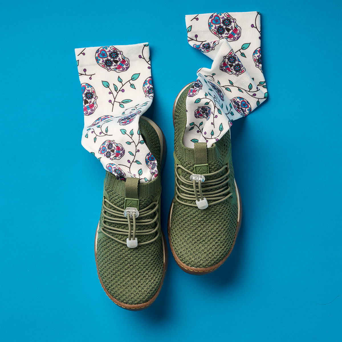 Align&trade; Torri slip on sneaker in Olive Green shown from overhead, with the Compression Socks 360 in Sugar Skulls coming out of the shoes.